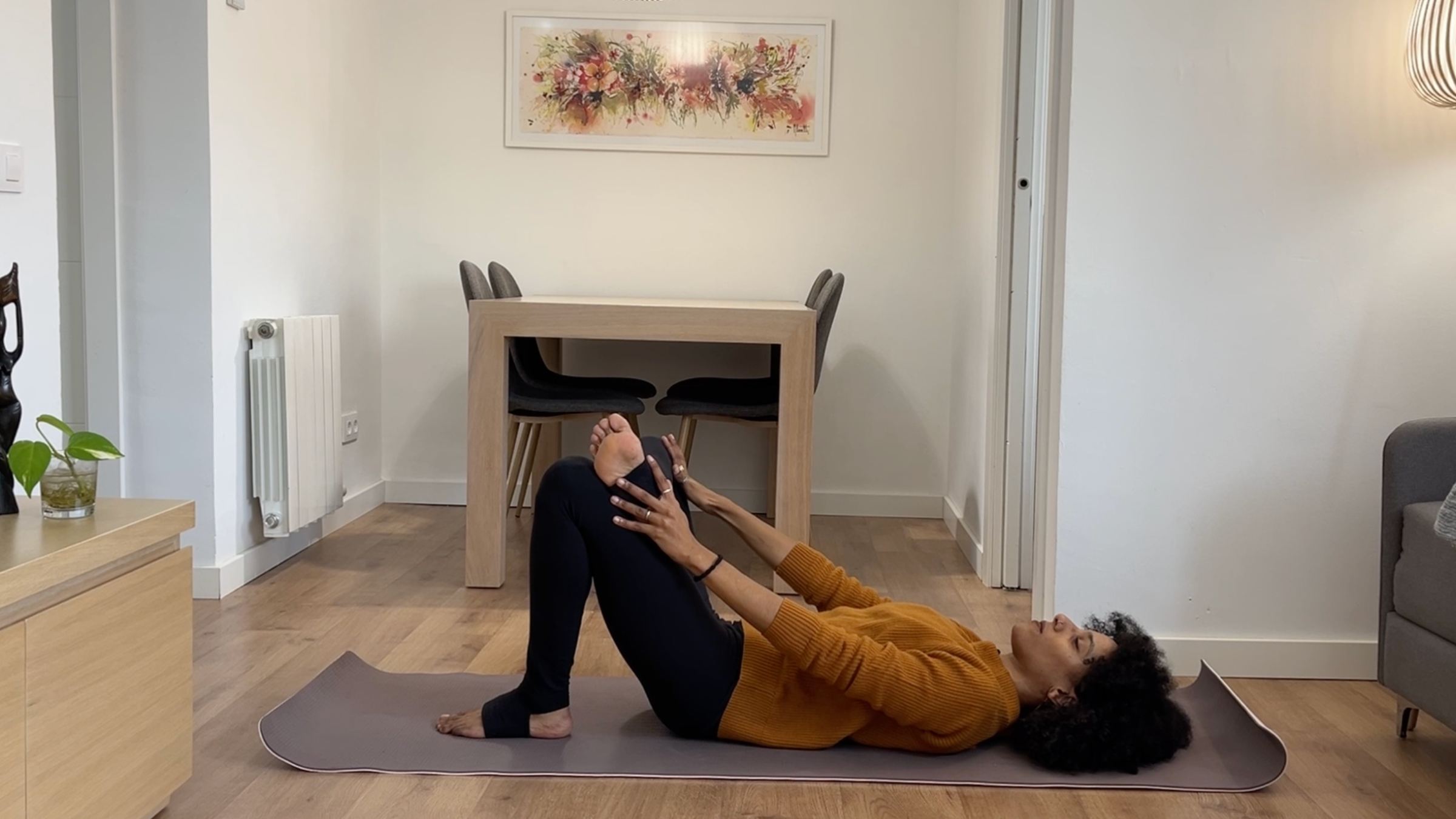 Laia Bové in reclined Figure 4 stretch with right ankle crossed over left knee and arms rested in a cactus shape.